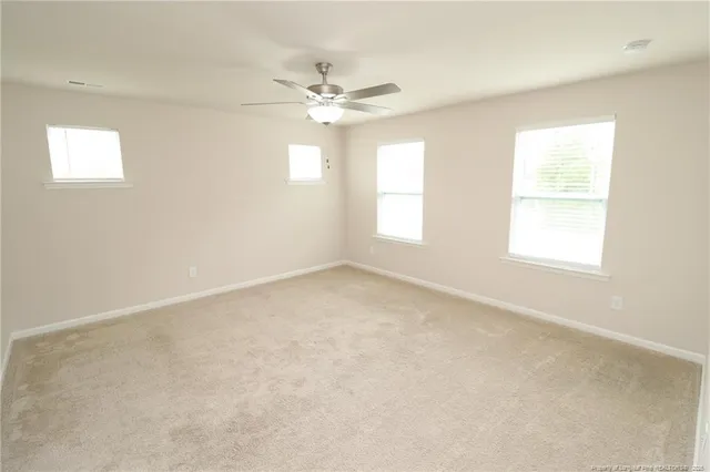an empty room with windows and fan