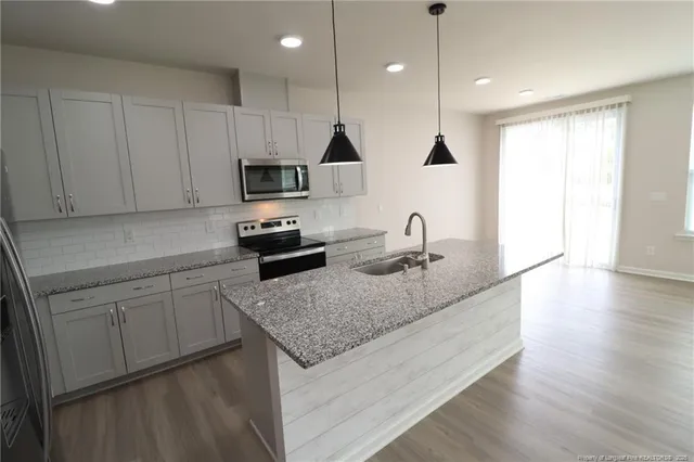 a kitchen with appliances cabinets and a wooden floor