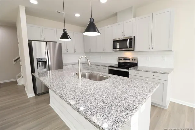 a kitchen with stainless steel appliances granite countertop a sink a stove and a refrigerator