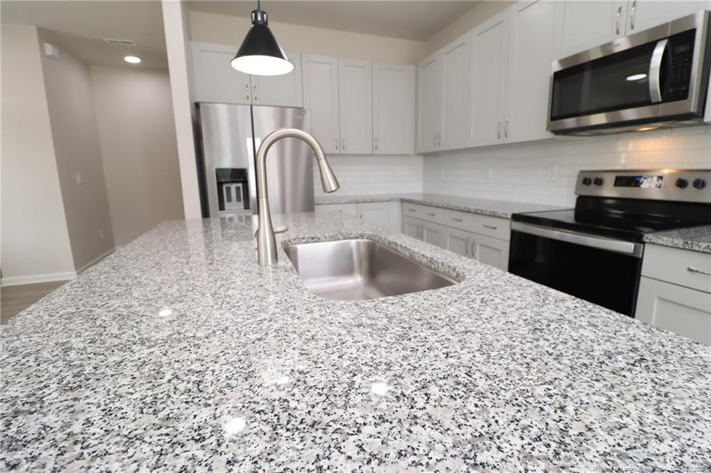 104 Kineton Woods Way Garner, NC 27529 - Photo 7 of 43 a kitchen with kitchen island granite countertop a sink and a stove top oven