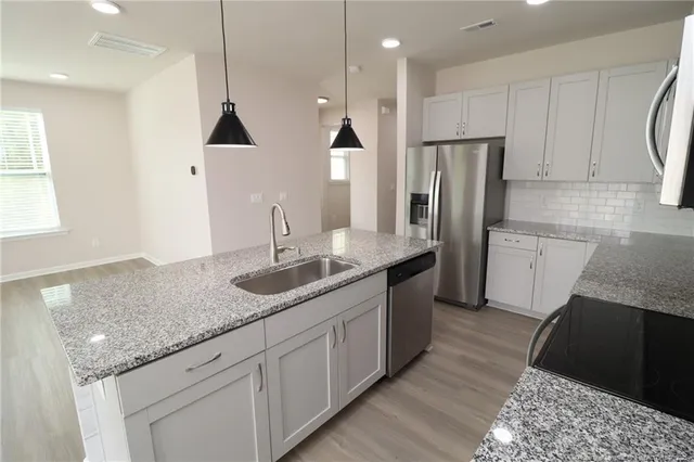 a kitchen with granite countertop a sink a counter top space stainless steel appliances and cabinets