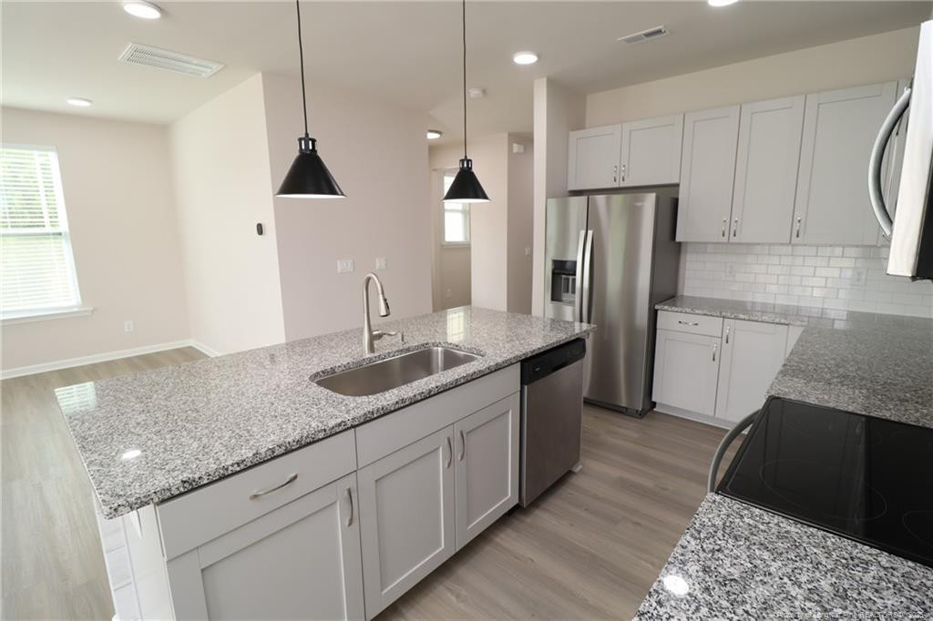 104 Kineton Woods Way Garner, NC 27529 - Photo 8 of 43 a kitchen with granite countertop a sink a counter top space stainless steel appliances and cabinets