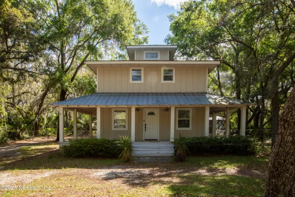 a view of a white house with large windows and a large tree