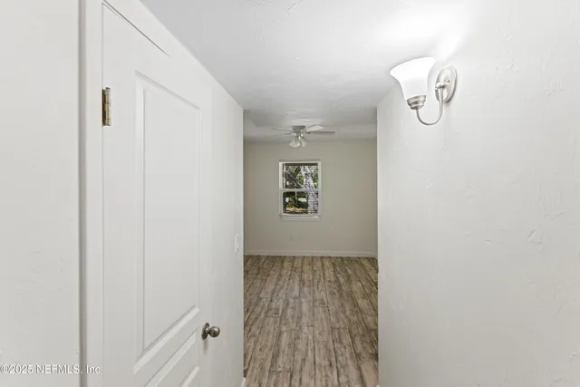 a view of an empty room with window and wooden floor