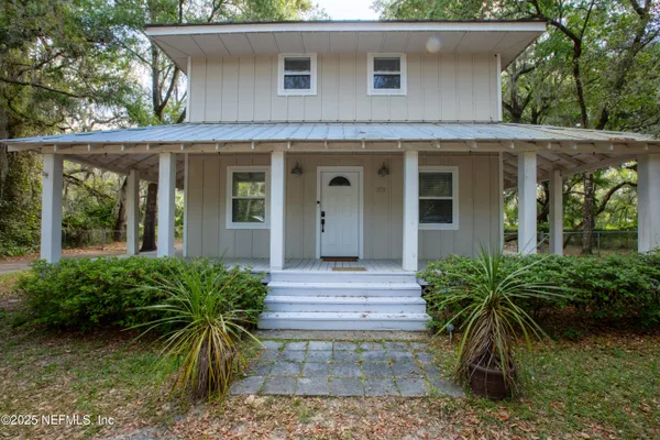 a view of a house with a yard and large trees