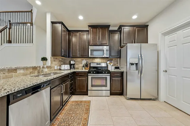 a kitchen with stainless steel appliances granite countertop a refrigerator stove and sink