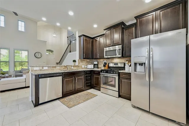 a kitchen with stainless steel appliances granite countertop a refrigerator a sink dishwasher a stove with white cabinets