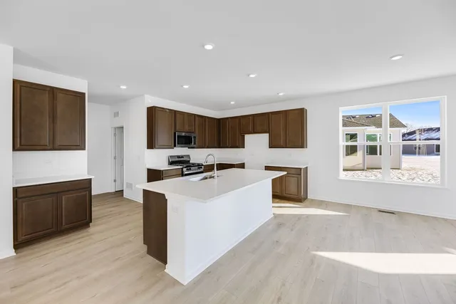 a large white kitchen with stainless steel appliances granite countertop a stove a sink dishwasher and a refrigerator with wooden floor