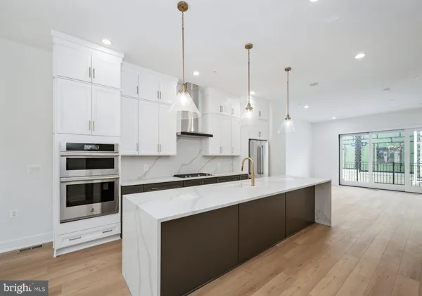 a large kitchen with stainless steel appliances kitchen island granite countertop a stove a sink and white cabinets with wooden floor