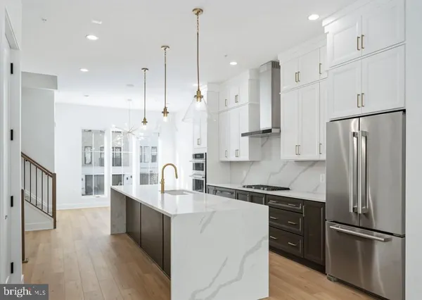 a kitchen with stainless steel appliances granite countertop a refrigerator a sink and wooden floors