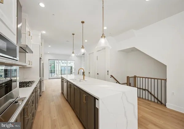 a large kitchen with kitchen island a large counter space a sink stainless steel appliances and cabinets