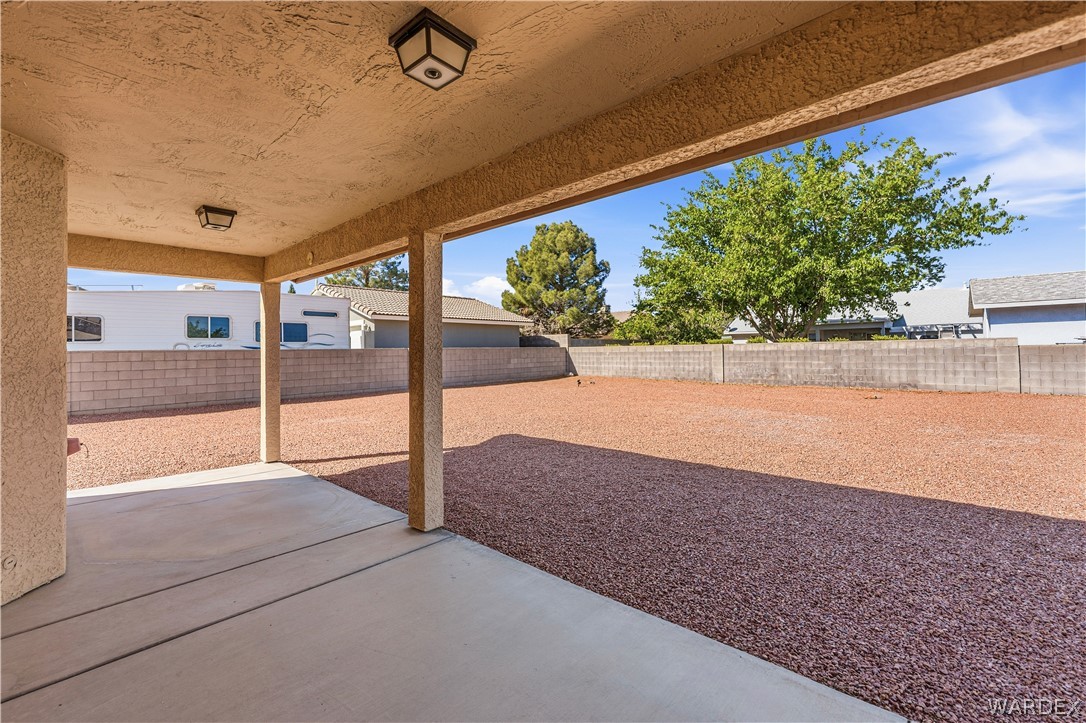 3973 Prairie View Drive Kingman, AZ 86409 - Photo 28 of 34 The property features a covered patio with an outdoor ceiling light fixture, extending to an expansive outdoor area with red gravel