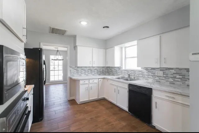 an empty room with chandelier fan and windows