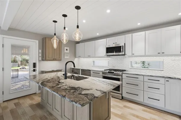 a kitchen with granite countertop a sink a stove and cabinets