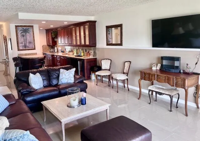 a living room with furniture a flat screen tv and kitchen view