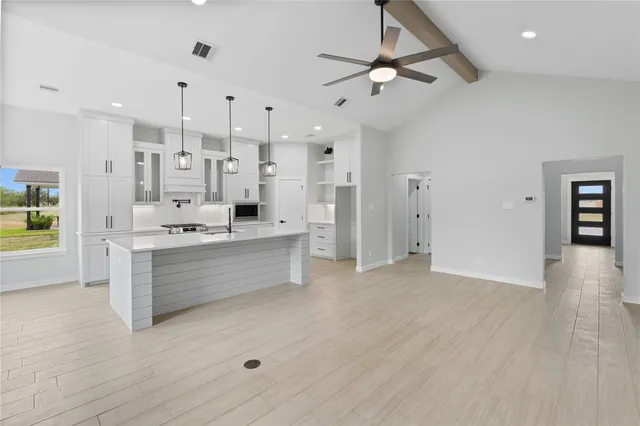 a large kitchen with stainless steel appliances kitchen island a large counter top and a chandelier