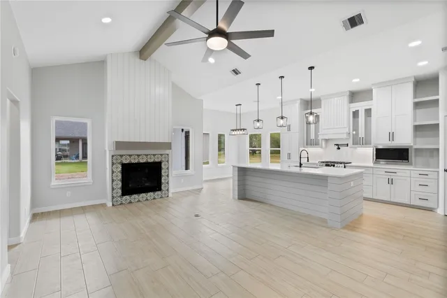a large kitchen with stainless steel appliances a large counter top a stove and a fireplace