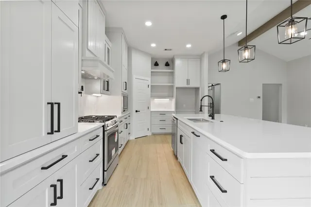 a large kitchen with kitchen island a stove a sink a center island and a wooden floor