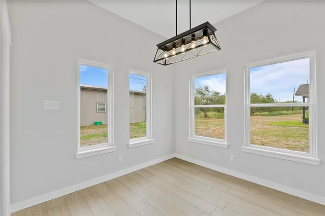 a view of an empty room with a window and kitchen view