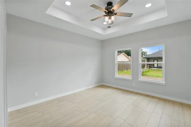 an empty room with windows and ceiling fan