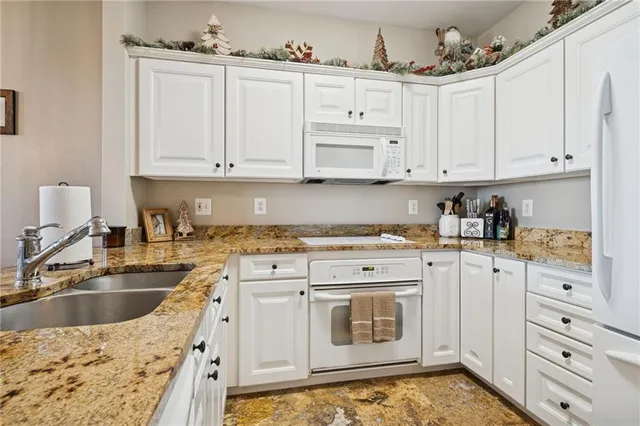 a kitchen with granite countertop a sink stove and cabinets