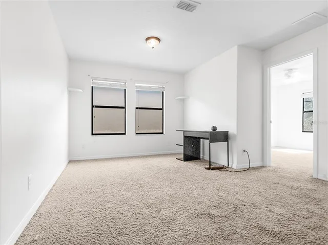 an empty room with windows and fan