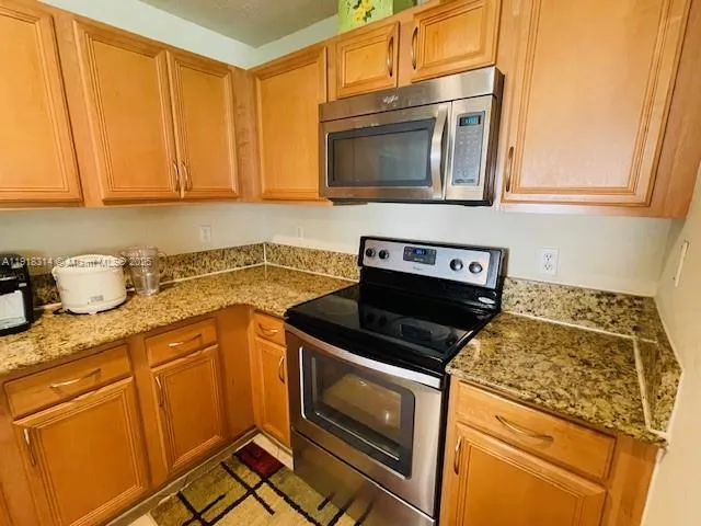 a kitchen with granite countertop a stove top oven microwave and cabinets