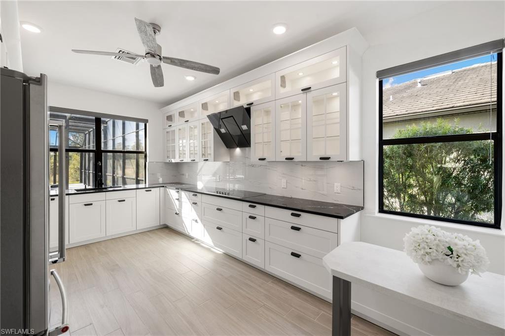 19824 Beverly Park Road Estero, FL 33928 - Photo 18 of 50 a kitchen with granite countertop a stove a sink and white cabinets with wooden floor