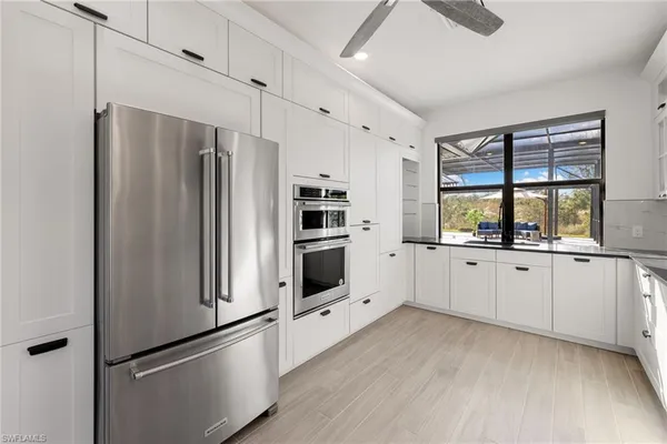 a large kitchen with stainless steel appliances kitchen island granite countertop a refrigerator and a stove top oven