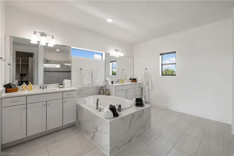 a bathroom with a bathtub a double vanity sink and a mirror