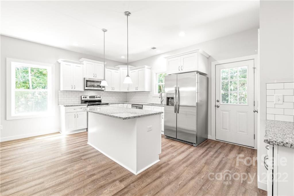 8621 Reedy Creek Road Charlotte, NC 28215 - Photo 11 of 22 a kitchen with stainless steel appliances a refrigerator a sink dishwasher a stove and white cabinets with wooden floor