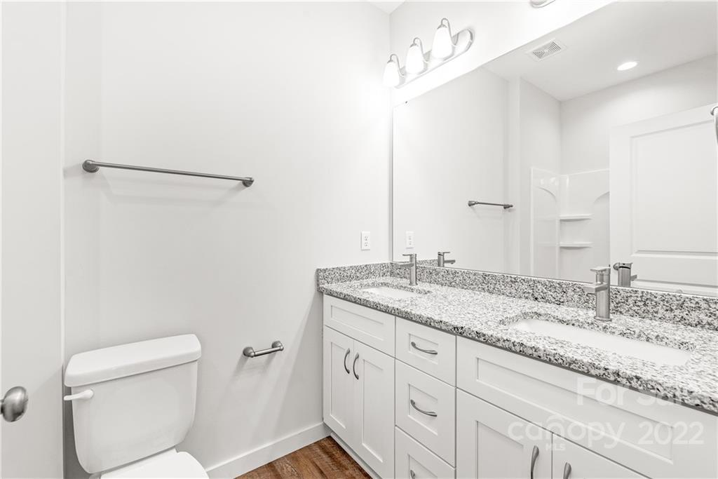 8621 Reedy Creek Road Charlotte, NC 28215 - Photo 16 of 22 a bathroom with a granite countertop sink a mirror and a toilet
