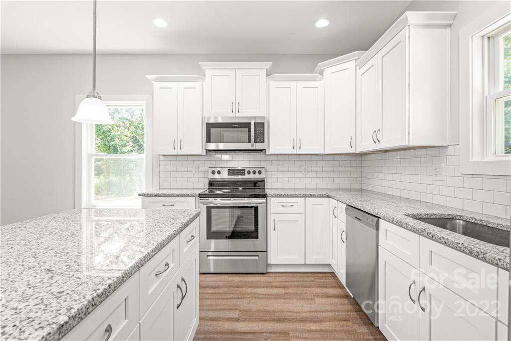 8621 Reedy Creek Road Charlotte, NC 28215 - Photo 9 of 22 a kitchen with granite countertop a sink stainless steel appliances and white cabinets