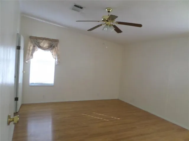 an empty room with a window and a ceiling fan