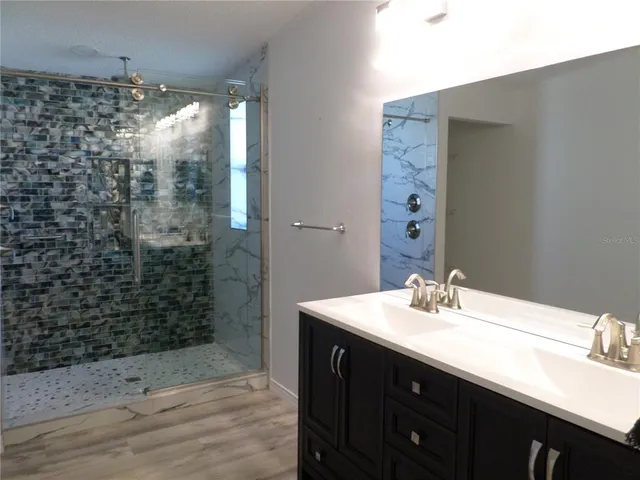a bathroom with a sink shower and a mirror