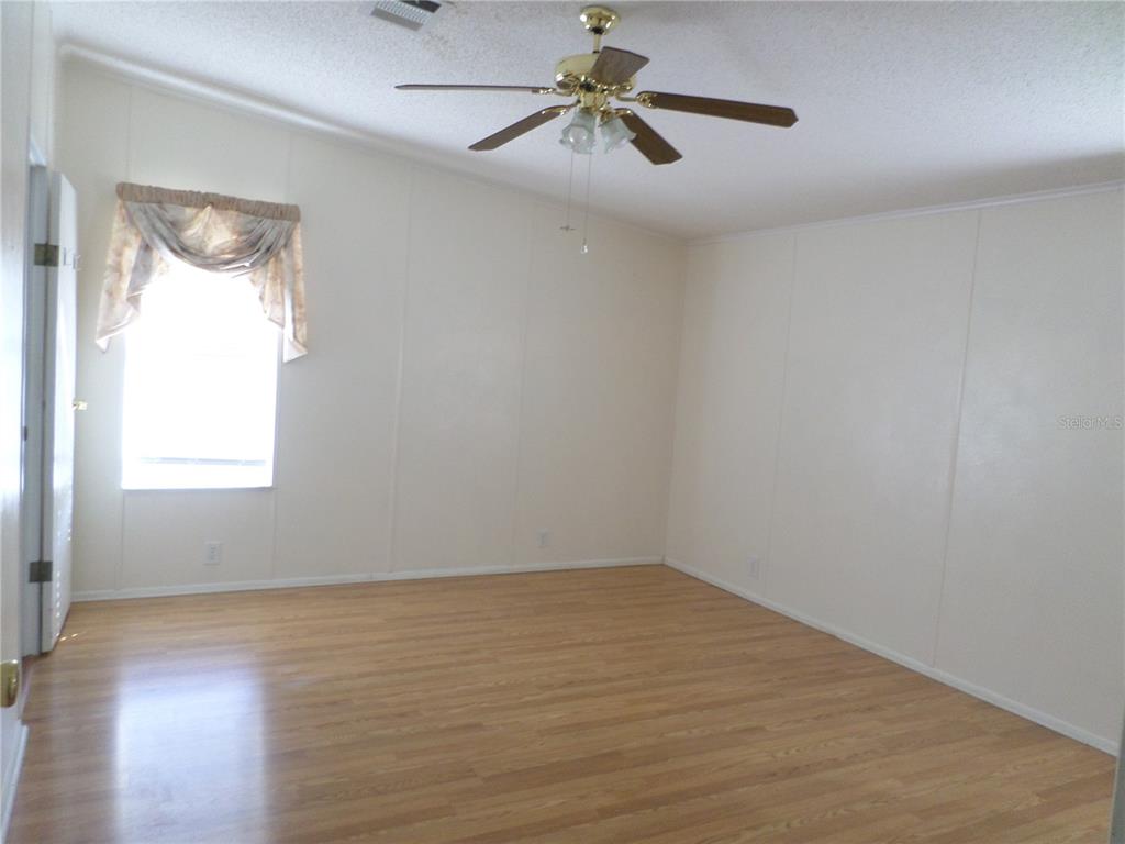 1690 Southwest 35th Circle Okeechobee, FL 34974 - Photo 18 of 23 an empty room with wooden floor ceiling fan and windows