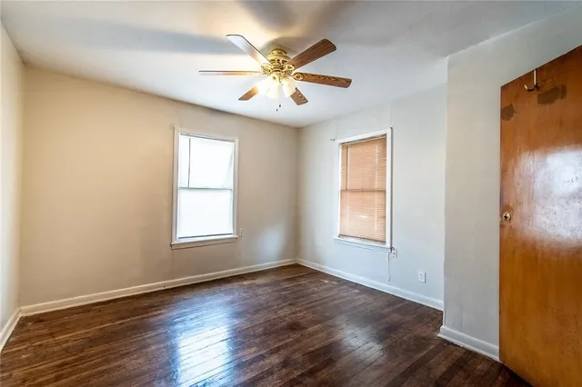 an empty room with wooden floor fan and windows