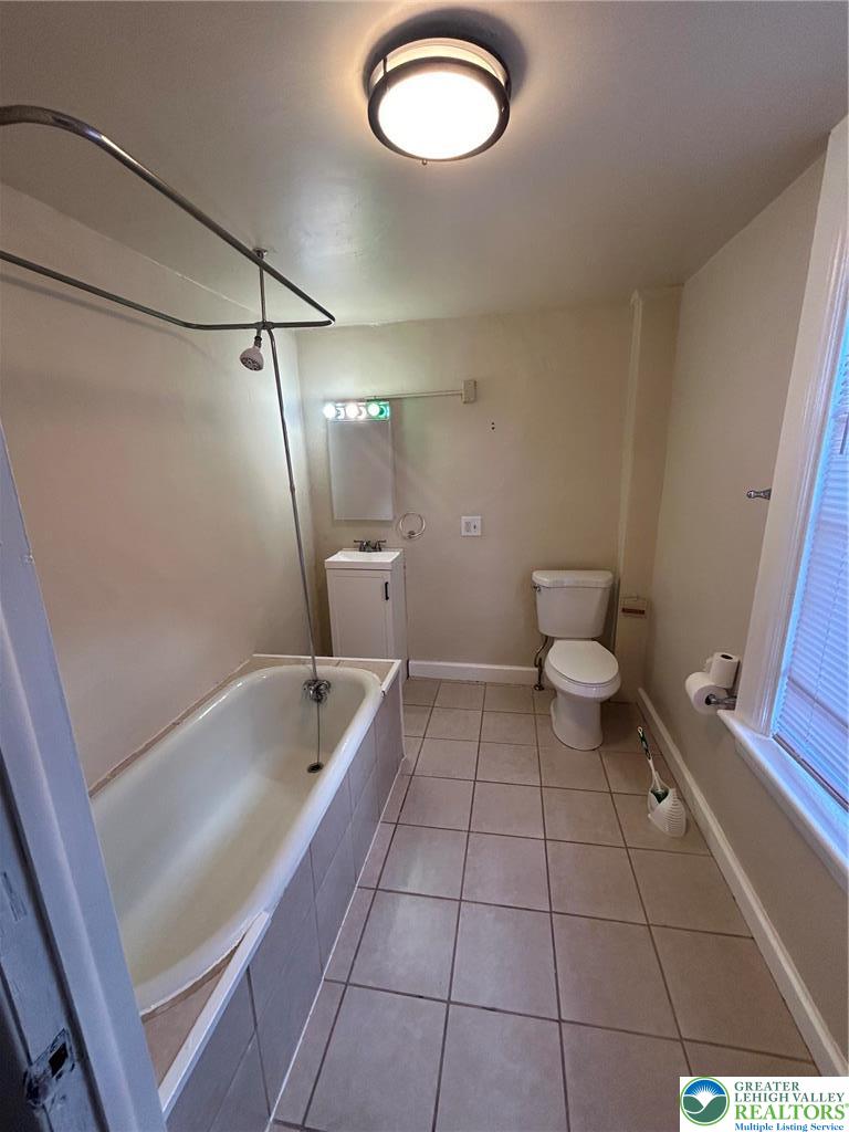 1122 East 4th Street Bethlehem, PA 18015 - Photo 8 of 13 A well-lit primary bathroom features a combination tub and shower, complete with tiled surrounds.