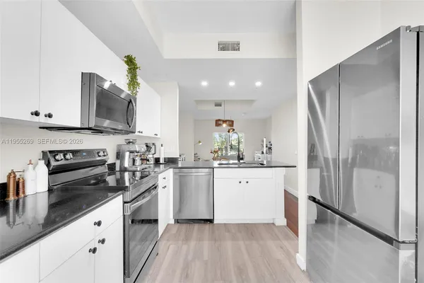 a kitchen with stainless steel appliances a refrigerator sink and white cabinets