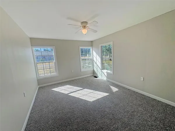 an empty room with windows and ceiling fan
