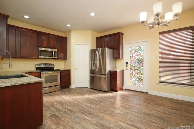 a kitchen with granite countertop wooden floors stainless steel appliances and a window