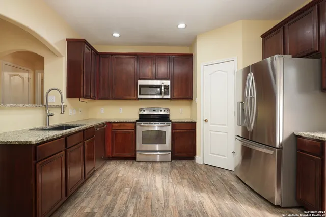 a kitchen with granite countertop wooden cabinets a refrigerator and a sink