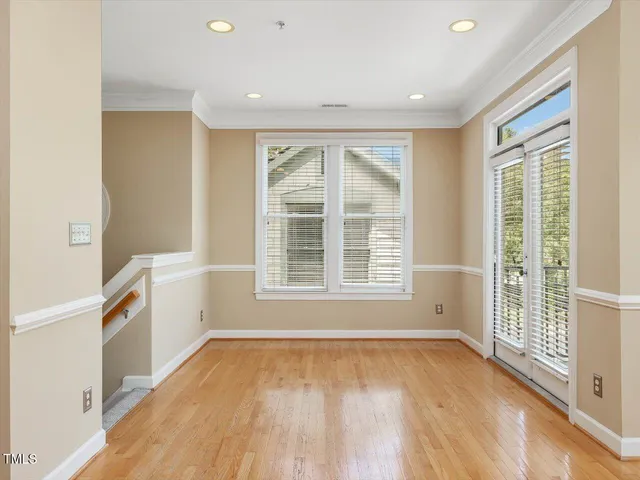 a view of an empty room with a window and wooden floor