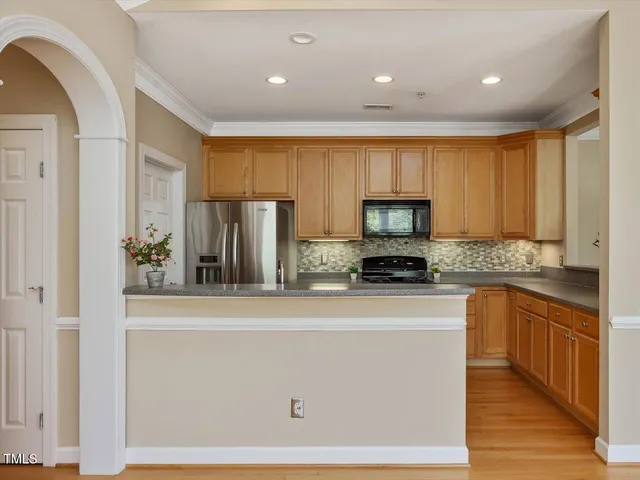 a kitchen with stainless steel appliances granite countertop a refrigerator a stove and a sink with wooden floor