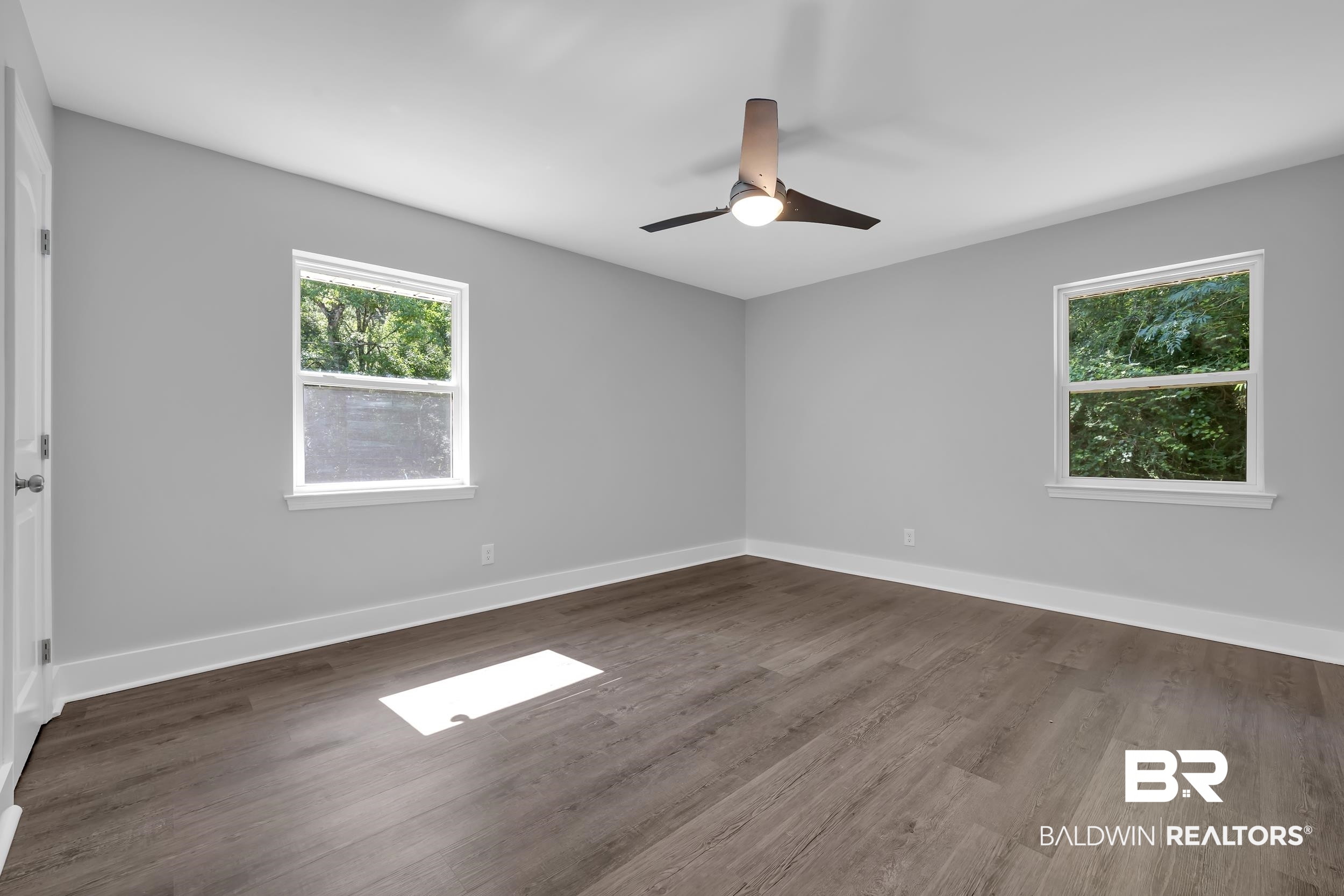 2712 Shelton Beach Rd Extension Mobile, AL 36613 - Photo 14 of 24 Spacious room featuring wood-finish flooring, two large windows, a modern ceiling fan with integrated lighting, and light grey wall finishes