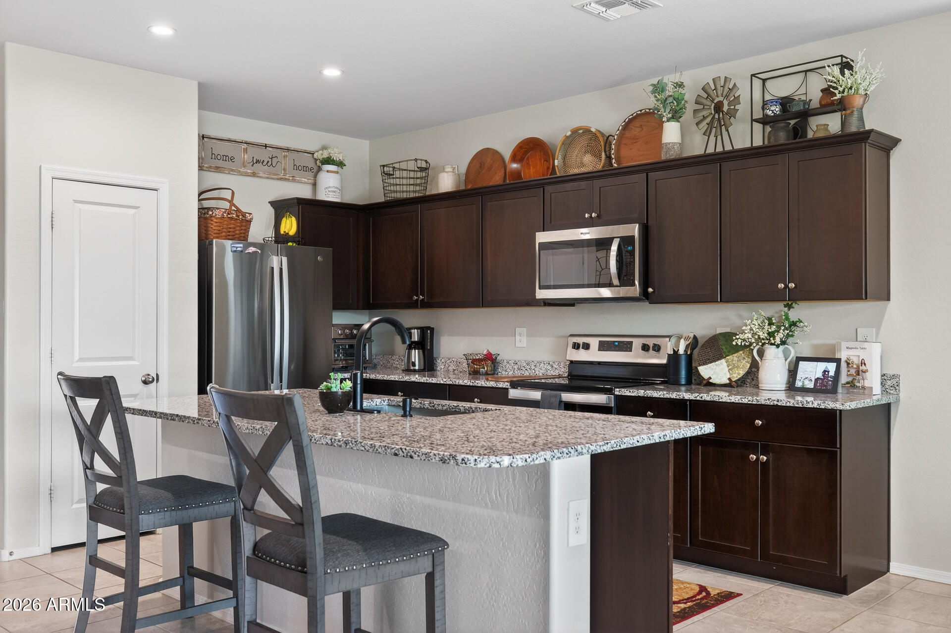9573 Cotton Road Florence, AZ 85132 - Photo 11 of 46 a kitchen with stainless steel appliances granite countertop a stove top oven a refrigerator a sink and chairs