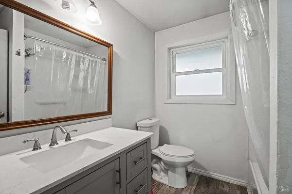 a bathroom with a granite countertop toilet a sink and a mirror