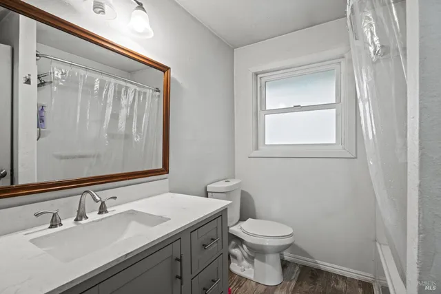 a bathroom with a granite countertop toilet a sink and a mirror