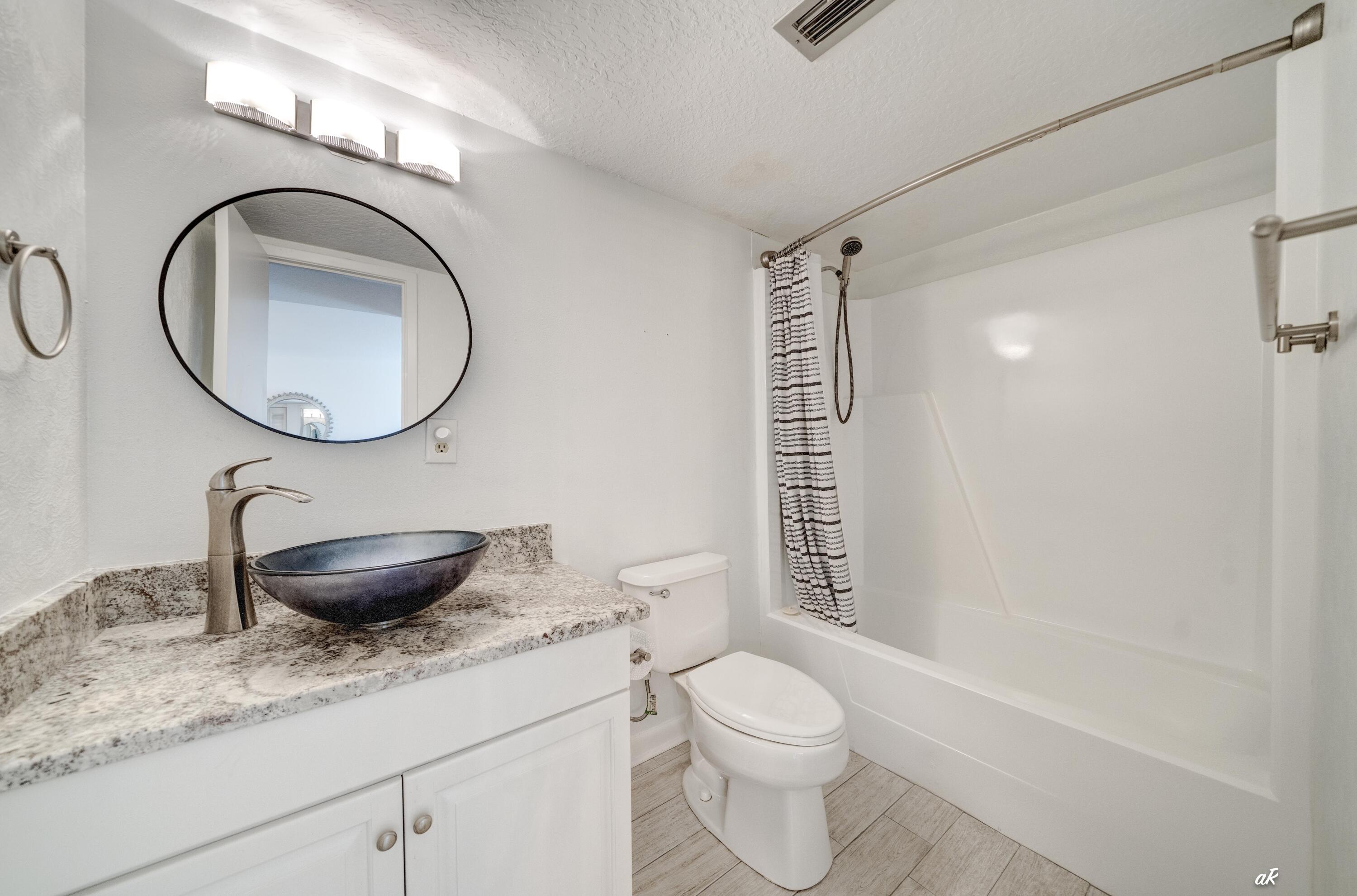 30 Moreno Point Road, Unit 404A Destin, FL 32541 - Photo 23 of 52 a bathroom with a granite countertop toilet sink and mirror