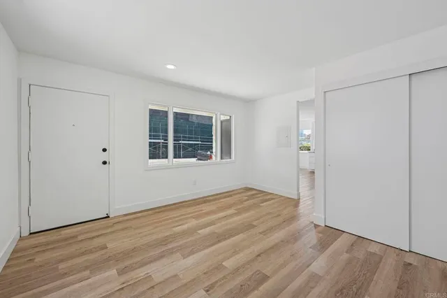 a view of an empty room with wooden floor and windows